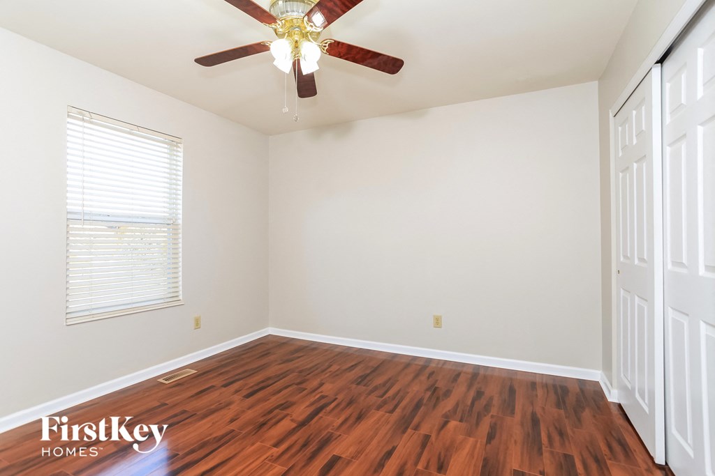 A room with a ceiling fan and wooden flooring.
