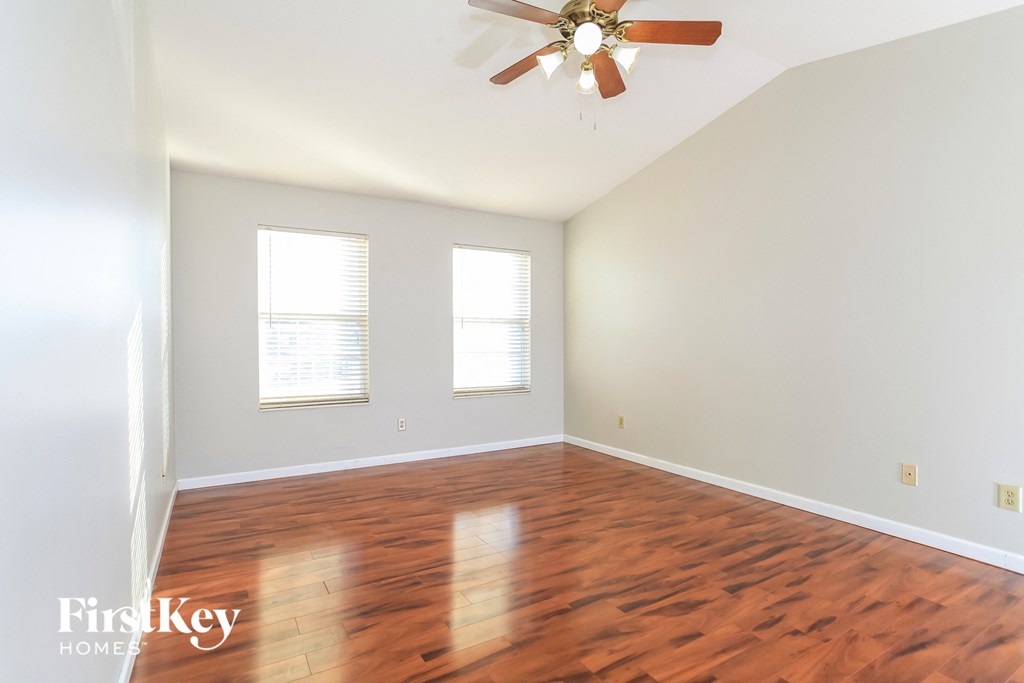 A room with a ceiling fan and wooden flooring.