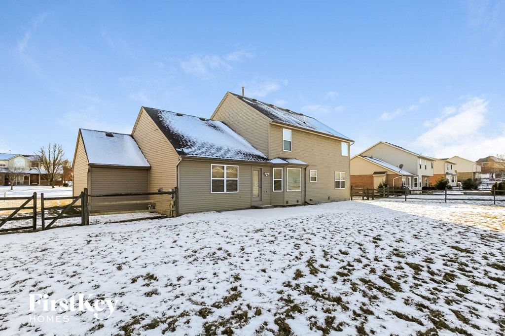 A house with a snow-covered roof and a fence in front of it.
