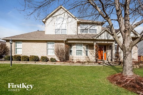 a white brick house with a tree in the front yard