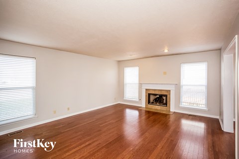 the living room with wood floors and a fireplace