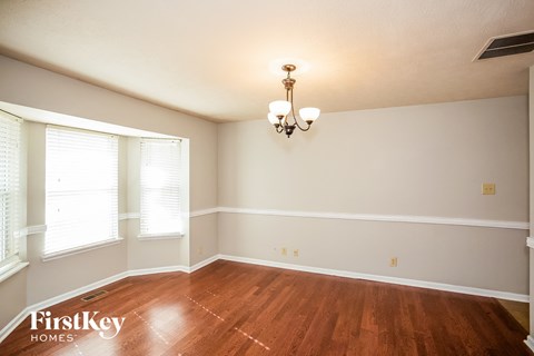 a empty dining room with wood floors and a chandelier