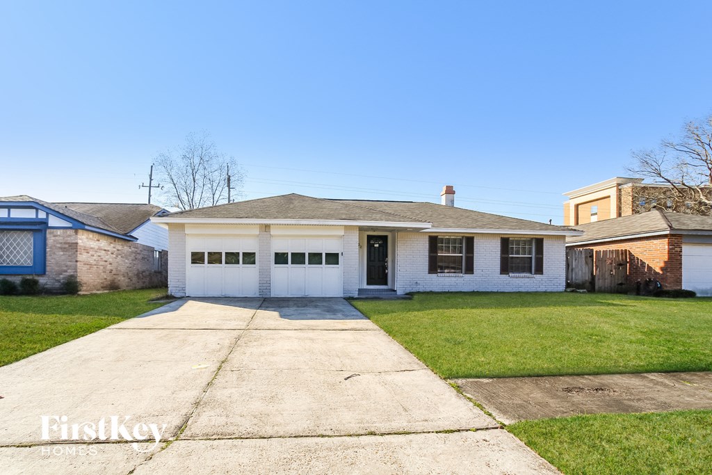 a small white house with a driveway and grass