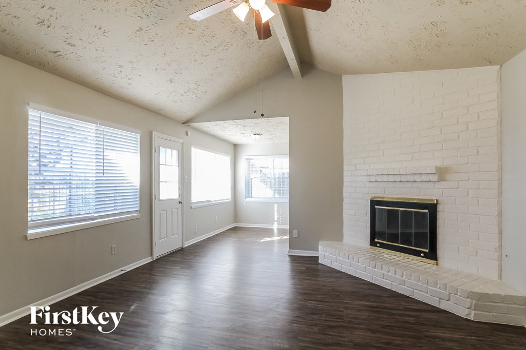 an empty living room with a fireplace and a ceiling fan