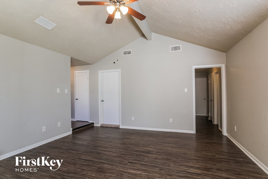 the living room of an empty house with a ceiling fan