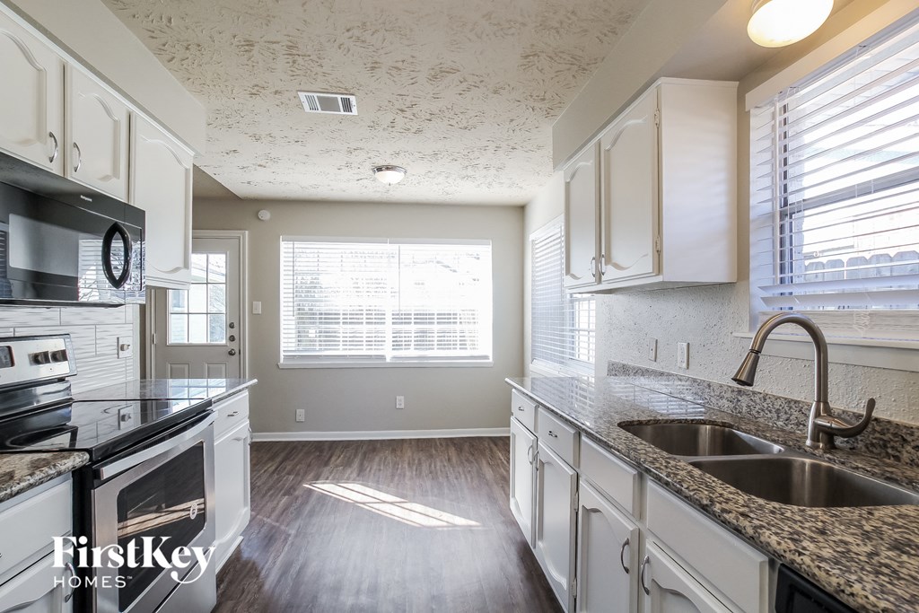 a kitchen with white cabinets and granite counter tops