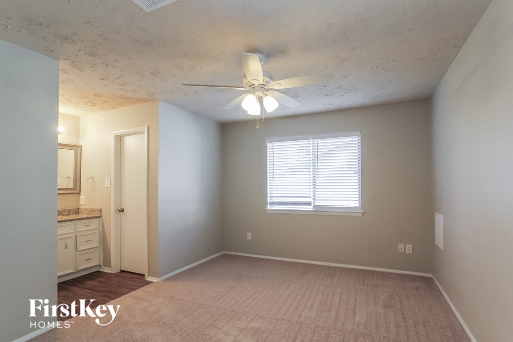 an empty room with a ceiling fan and a window