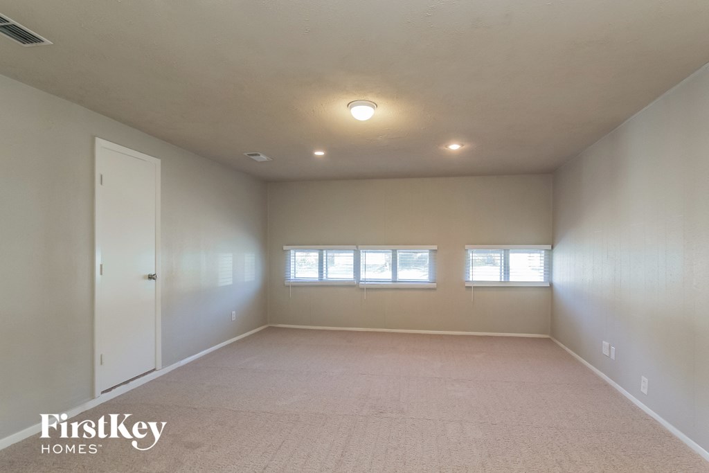 an empty living room with two windows and a ceiling light
