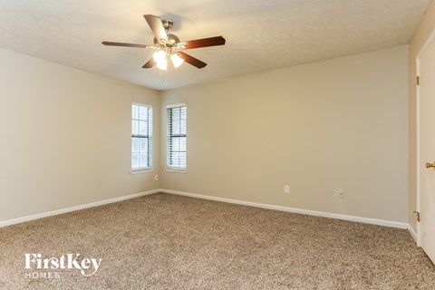 the spacious living room with ceiling fan and carpet