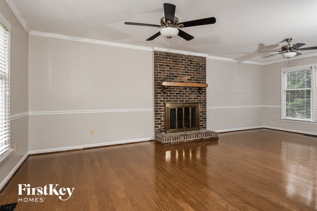 a living room with a brick fireplace and wooden floors and a ceiling fan