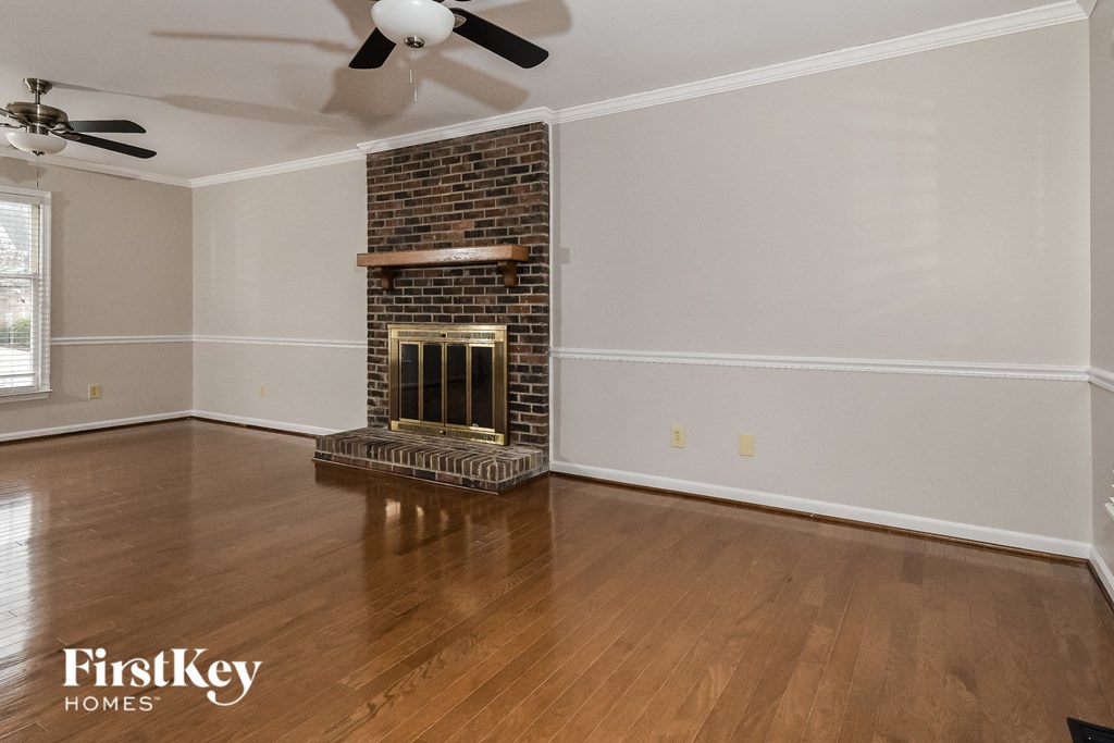 a living room with a brick fireplace and wooden floors
