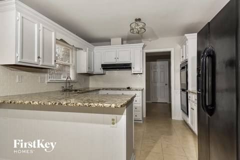 a kitchen with white cabinets and a marble counter top
