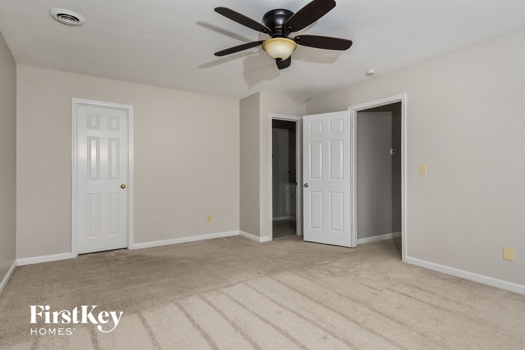 a empty living room with a ceiling fan and two doors