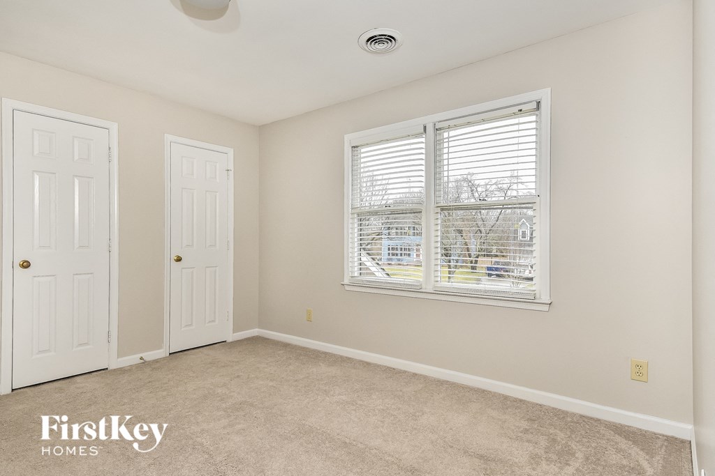 a bedroom with a window and a door and a carpeted floor