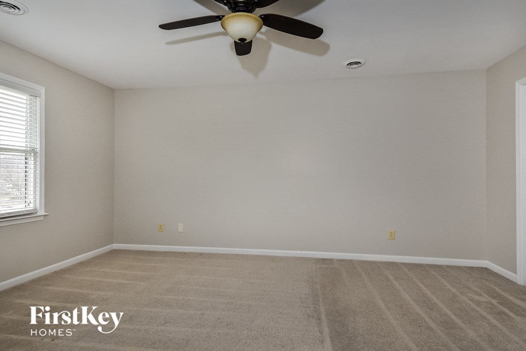 a empty room with a ceiling fan and a carpeted floor