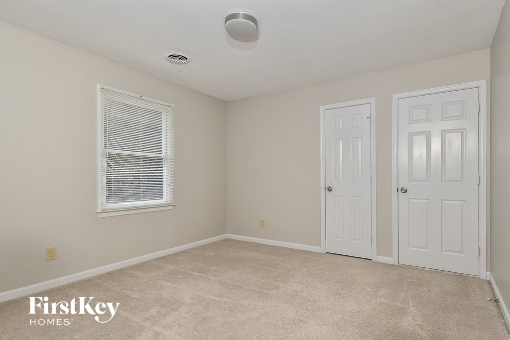 a bedroom with a carpeted floor and two white doors and a window