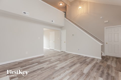 A spacious room with wooden flooring and a staircase leading to another room.