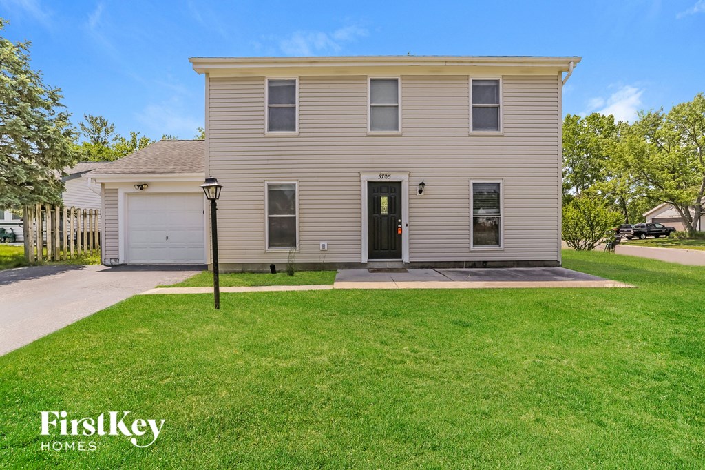 the front of a house with a lawn and a driveway