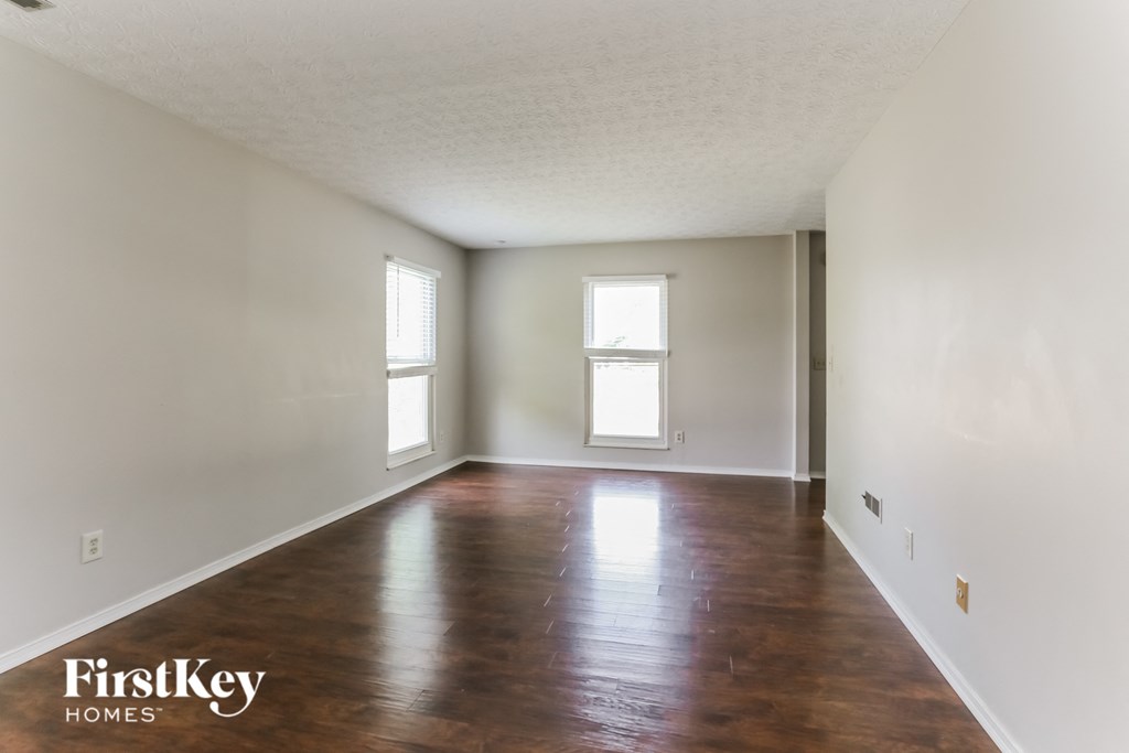 an empty living room with wood floors and white walls