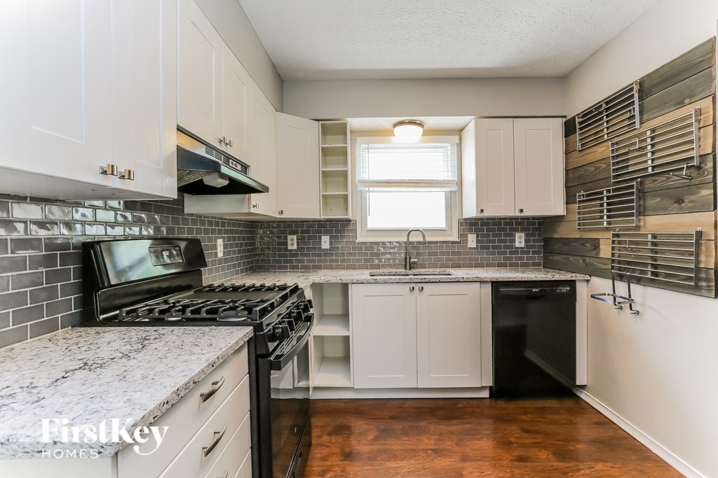 a kitchen with white cabinets and black appliances and a window