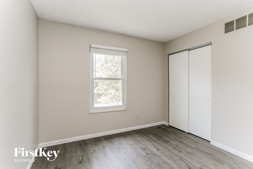 a bedroom with white walls and a window and wooden floors