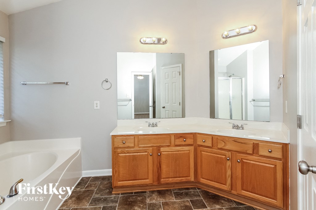 a bathroom with wooden cabinets and a tub and a sink