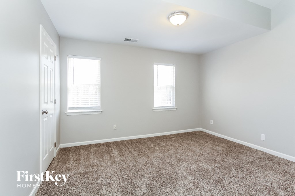 a bedroom with a carpeted floor and two windows