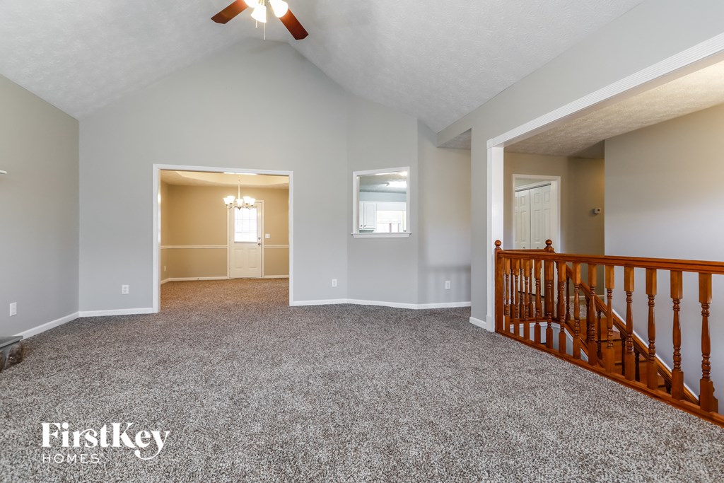 the living room and entryway of an empty house with gray walls and carpet