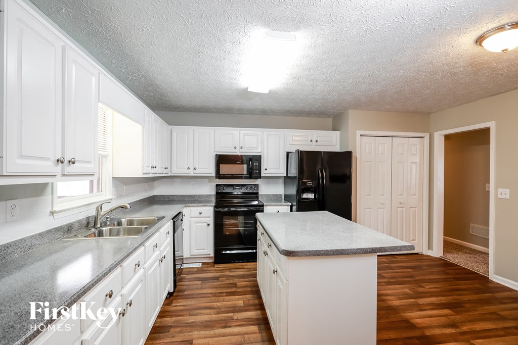 a kitchen with white cabinets and black appliances