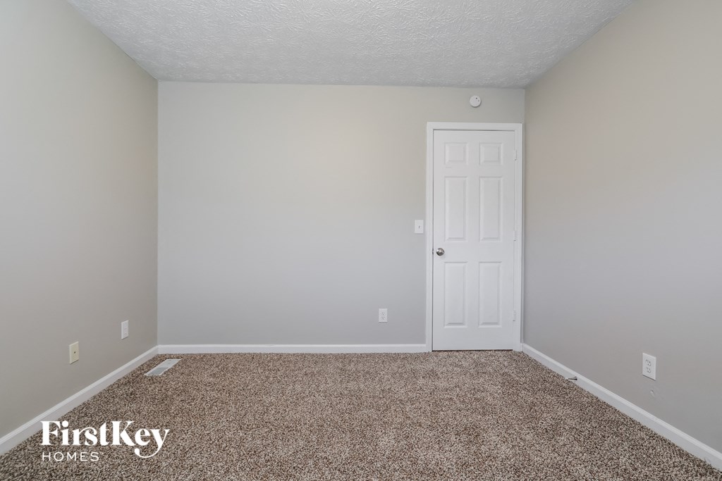 a bedroom with a white door and a carpeted floor