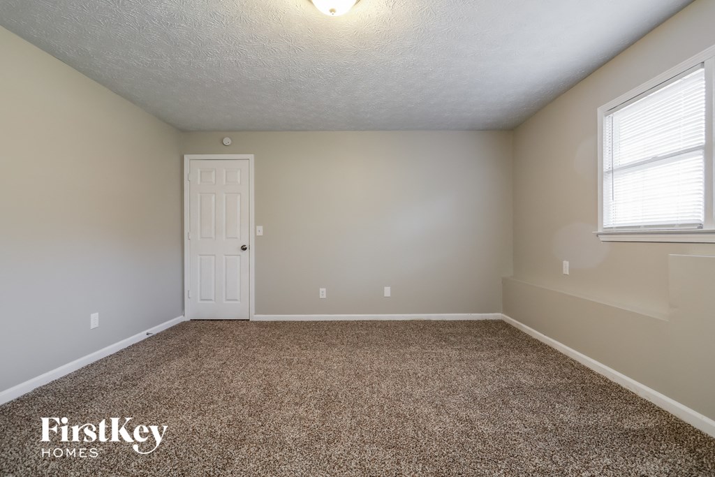 the spacious bedroom with carpeted flooring and a white door