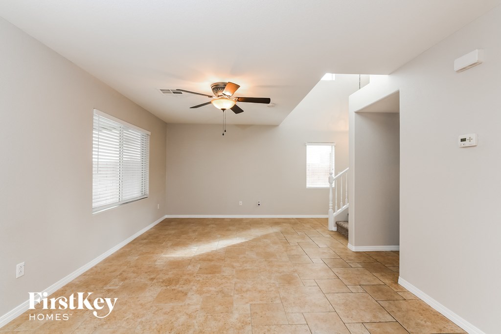 A spacious room with a ceiling fan and tiled floor.