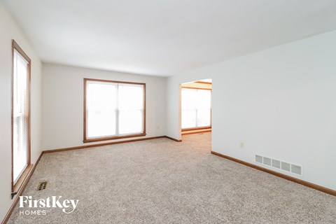 a living room with carpet and two windows