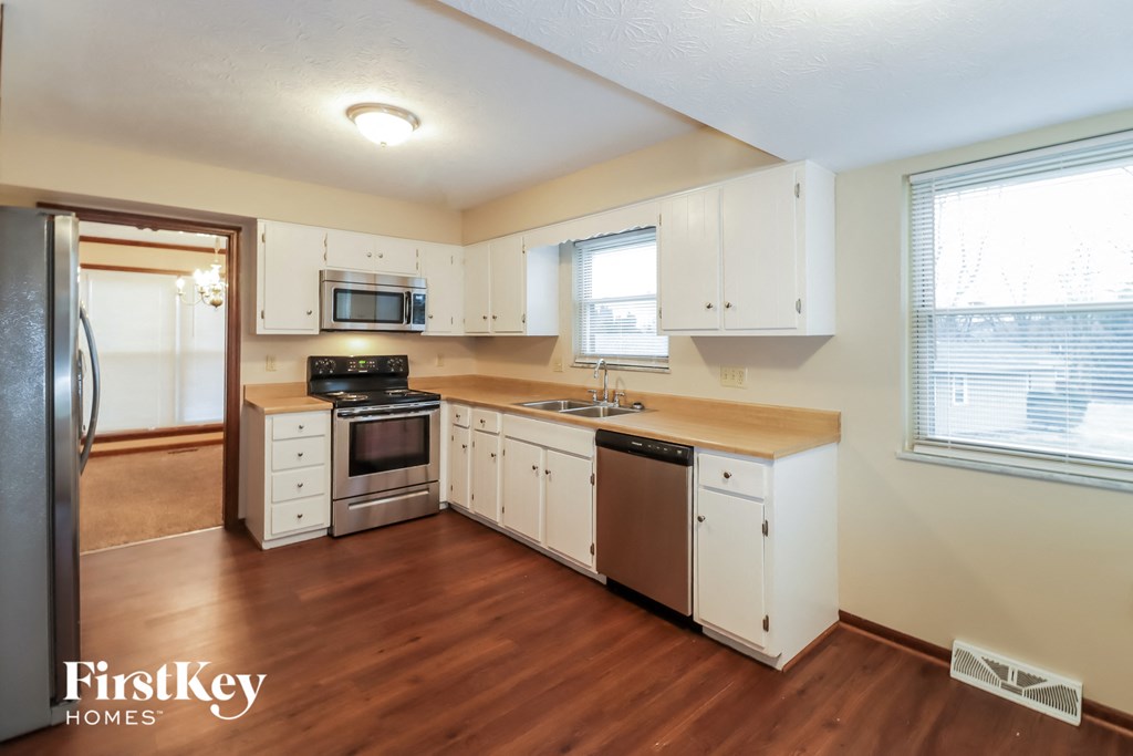 a kitchen with white cabinets and a wooden floor and a stove and refrigerator