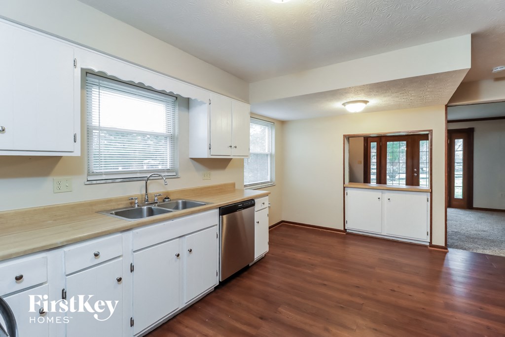 a kitchen with white cabinets and a sink and a window