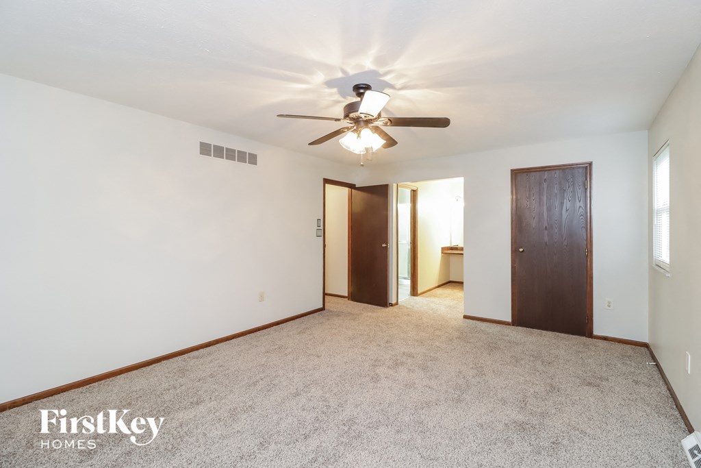 an empty living room with a ceiling fan and a closet