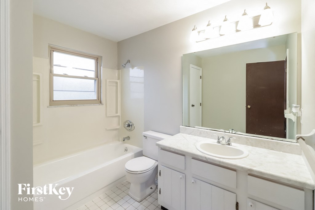 a white bathroom with a large mirror and a toilet and a sink