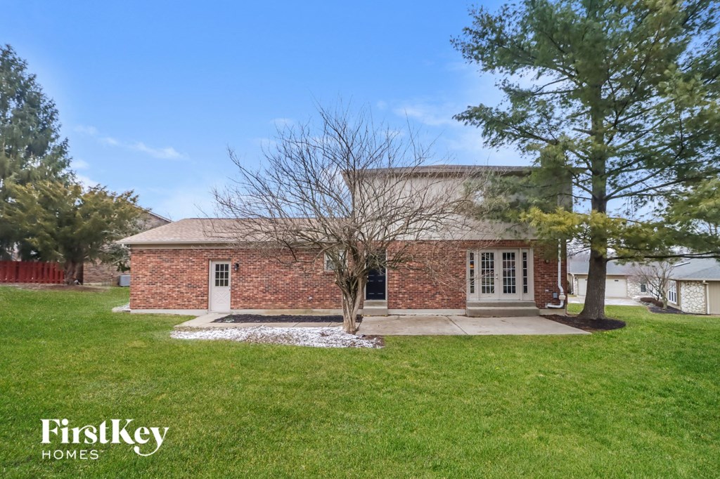 a small brick house with a yard and a tree