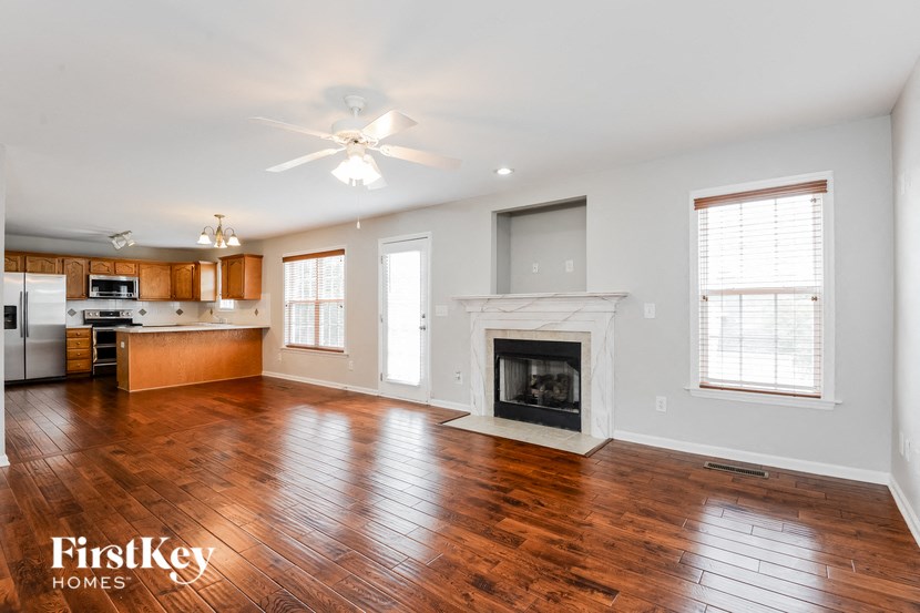 an empty living room with a fireplace and a kitchen