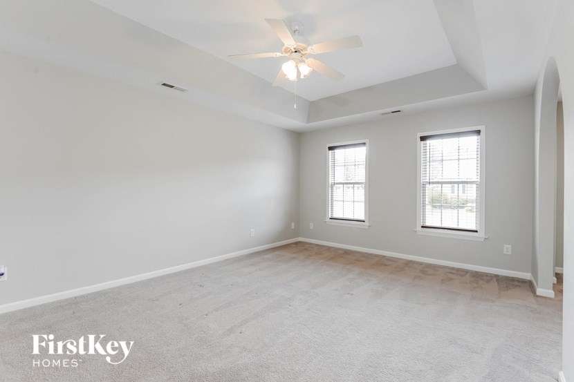 an empty living room with a ceiling fan and two windows