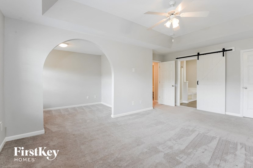 an empty living room with white walls and a ceiling fan