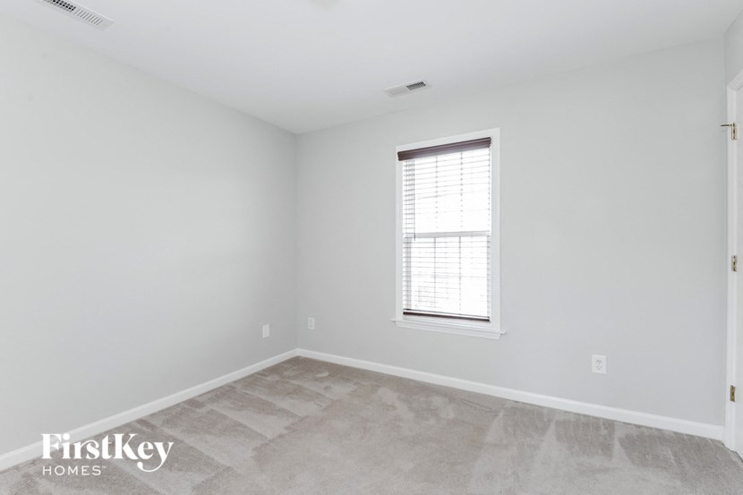 the living room of a home with white walls and a window