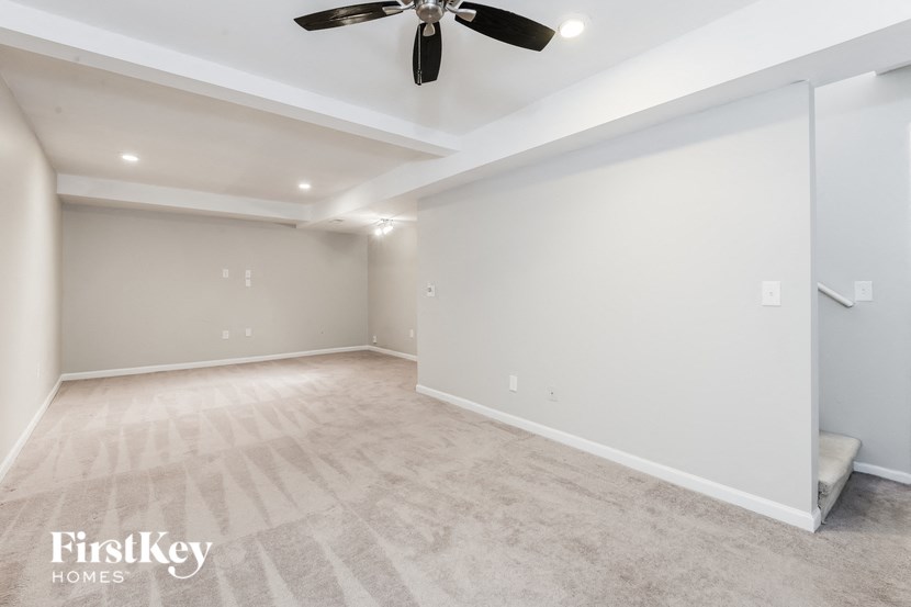 a empty living room with a ceiling fan and white walls
