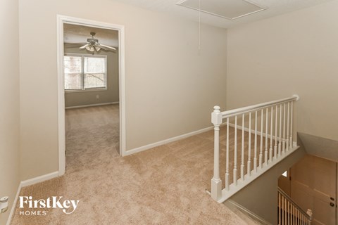 a bedroom with a staircase and a hallway with a ceiling fan