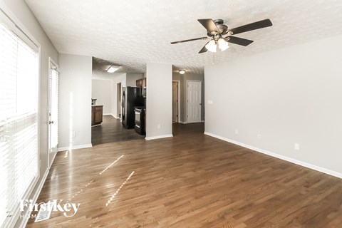 an empty living room with wood flooring and a ceiling fan