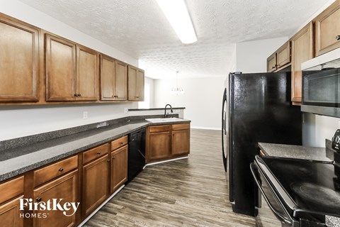 a kitchen with wooden cabinets and a black refrigerator