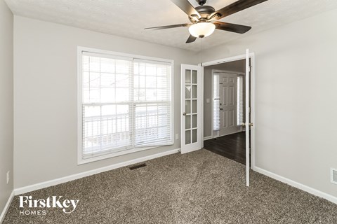 a bedroom with a ceiling fan and a door to a hallway