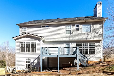 the back of a white house with a porch and a deck