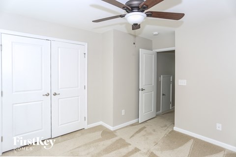 a bedroom with two closet doors and a ceiling fan