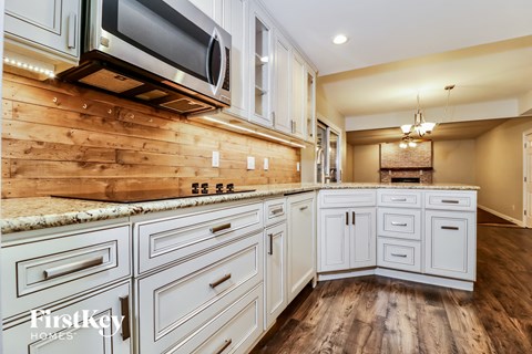 a kitchen with white cabinets and a wooden wall